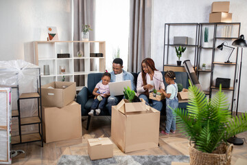 Parents with kids using laptop and packing boxes