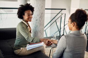 Happy African American businesswoman shakes hands with her mentor after meeting in the office. - Powered by Adobe