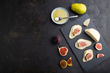 Summer appetizer with pear, cottage cheese, figs and honey on a black concrete background. Top view, copy space.