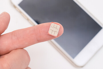 Micro sim card for mobile communication on a finger close up, wireless connection concept