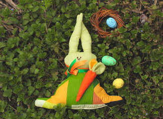 Easter bunny, cloth toy on the green grass. Colorful bright eggs