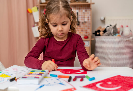 Portrait of small baby girl painting at home. Cute little child drawing Turkish flag picture. Turkish National Sovereignty and Children's Day or Commemoration of Atatürk Youth and Sports Day concept.