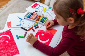 Portrait of small baby girl painting at home. Cute little child drawing Turkish flag picture. Turkish National Sovereignty and Children's Day or Commemoration of Atatürk Youth and Sports Day concept.