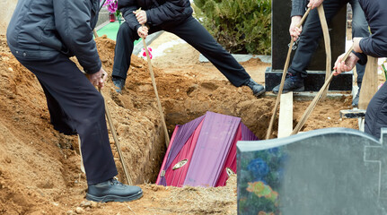 Burial. Men lower the coffin into the grave