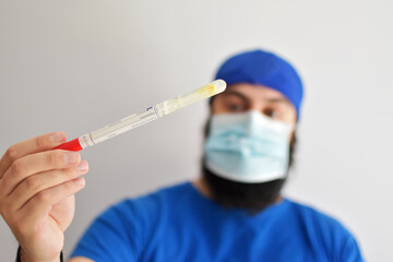 Nurse holding a tube. Rotavirus test. Man wearing a face mask grabbing a sample of feces to examined in a laboratory