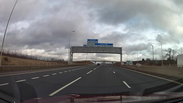 Dashcam view over the bonnet of a red car driving on the M8 motorway under a sign for Edinburgh and Eurocentral.