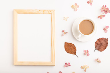Fototapeta na wymiar Composition with wooden frame, brown beech autumn leaves, hydrangea flowers and cup of coffee. mockup on white background. top view, copy space.