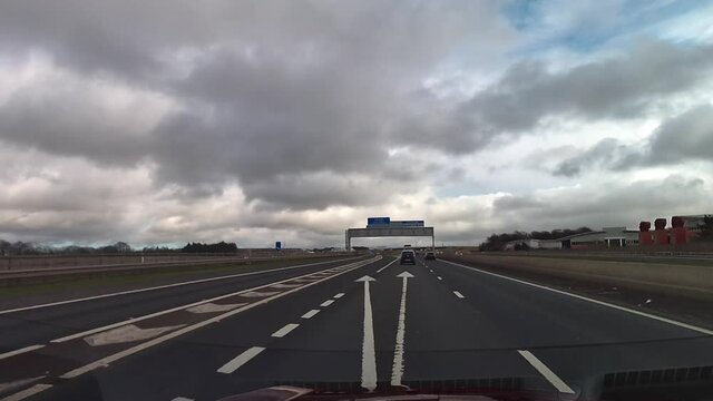Dashcam view over the bonnet of a red car driving on the M8 motorway under a sign for Edinburgh.