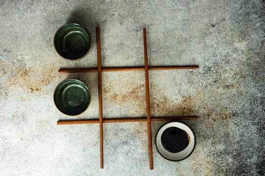 Overhead view of a game of noughts and crosses using Asian chopsticks and bowls