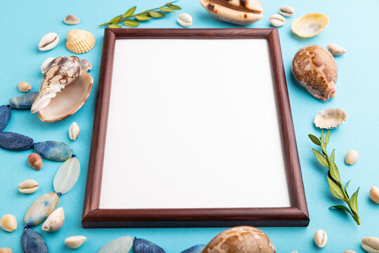 Composition with wooden frame, seashells, green boxwood. mockup on blue pastel background. side view, copy space.