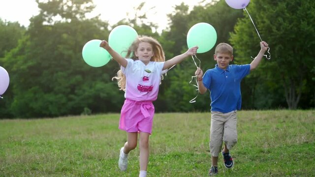Group of happy children playfully running with multicolored balloons