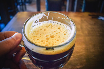 Hand holding a glass of dark beer