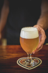 Waiter holding a glass of beer in pub
