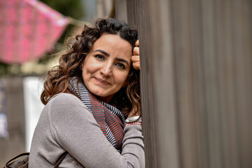 WOMAN WITH CURLY HAIR AND EMBROIDERED SCARF SMILING