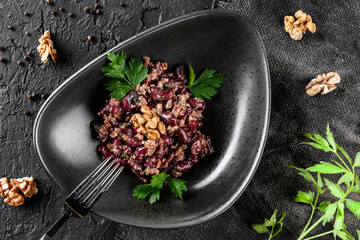 Tasty black bean salad with greens and nuts served on in a plate over a dark background. Concept of healthy food, clean eating, top view