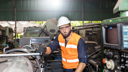 Mechanical engineer or worker in safety set working with heavy machine in a factory with light reflection background