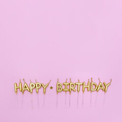 Happy Birthday words are made of golden candles on pastel pink background decorated with confetti star. Minimal birthday concept. Copy space, flat lay. Greeting card template.