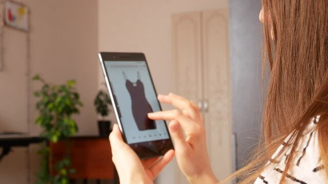 A young woman chooses a dress in an online store and adds it to cart close-up