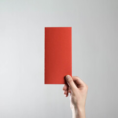 The hand holds a red flyer. A clean flyer in your hands. For your text. Isolated on a gray background.
