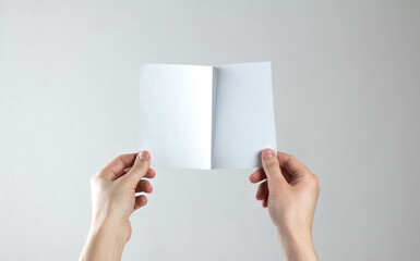 Hands holding a white folding flyer. A clean flyer in your hands. For your text. Isolated on a gray background