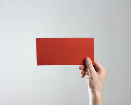 The hand holds a red flyer. A clean flyer in your hands. For your text. Isolated on a gray background.