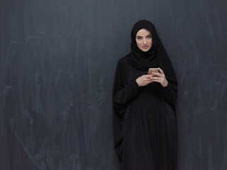 Young muslim businesswoman in traditional clothes or abaya using smartphone