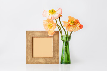 Natural real poppy flowers in green vase with vintage empty frame for tex, invitation, the menu on white background
