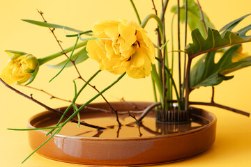 decorative floral floristic decoration with fresh tulips and yellow flowers in the blown pot looks like Japanese ikebana