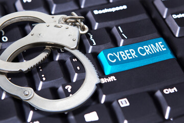 Handcuff with cybercrime text on keyboard