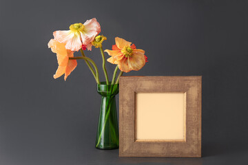 Natural real poppy flowers in green vase with vintage empty frame for tex, invitation, the menu on black background