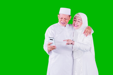 Muslim elderly couple using mobile phone on studio