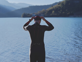 authentic triathlon athlete getting ready for swimming training on lake