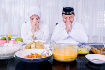 Young couple praying before dinner at Eid Mubarak