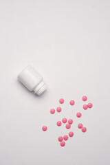 White jar with pills on a light background top view medicine health vitamins