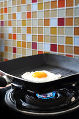 fried egg on a frying pan with burning flame on gas strove