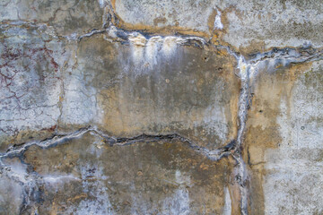 Concrete wall that is heavily cracked with age textured background.