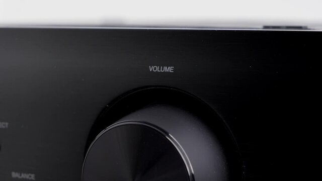 Turning up the volume of a black stereo amplifier. Audio equipment to listen to loud music at home. Modern technology used for parties, celebrations and events.