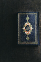 The Holy Al Quran on dark brown background. 