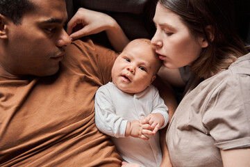 Man and his wife bonding with their small newborn kid while laying