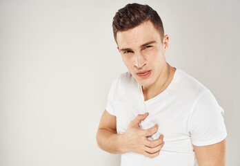 Guy in a white T-shirt sadness emotions model light background gesticulate with his hands
