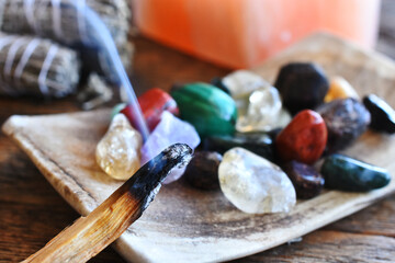 A close up image of a burning incense stick and healing crystals. 