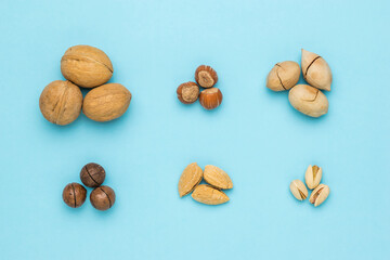 Piles of various unpeeled nuts on a blue background.