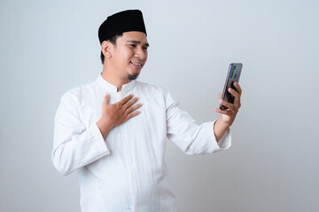 Muslim man smiling taking a video call to communicate with his family during Ramadan