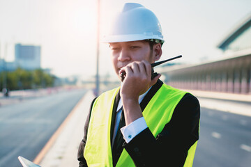 Asian manager engineer with hardhat,work outside industry,use digital tablet,radio communication control,with walkie talkie,work survey building construction factory site,business working and industry