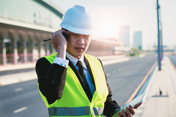 Asian manager engineer with hardhat,work outside industry,use digital tablet,radio communication...