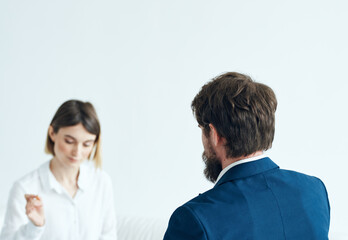 A woman with documents listens to the problems of a man on a light background psychologist