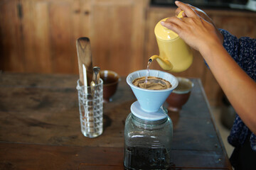 barista preparing brewing coffee with coffee maker and drip kettle.