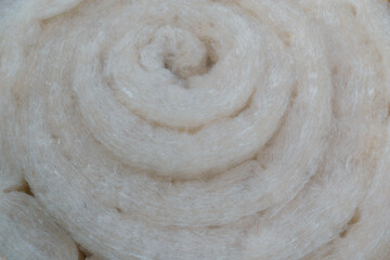 A roll of synthetic mineral material for thermal insulation of structures in the construction of buildings. The nap mattress is tightly rolled in circles.