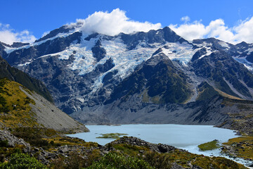 Fototapeta na wymiar spectacular view of rugged mountain peaks and a glacial lake along the hooker valley track on a sunny summer day, near mount cook village, on the south island of new zealand