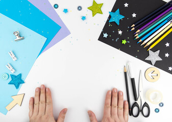 Creativity concept with children. Female hands on a white background, around blue and black paper, colored pencils, scissors and glue with space for text.